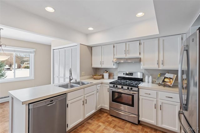 kitchen featuring appliances with stainless steel finishes, a peninsula, under cabinet range hood, a sink, and recessed lighting