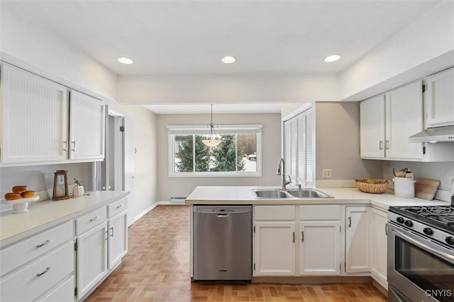 kitchen with appliances with stainless steel finishes, white cabinets, a sink, a peninsula, and under cabinet range hood