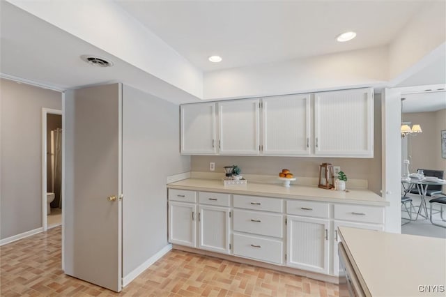 kitchen featuring brick floor, visible vents, baseboards, white cabinetry, and light countertops