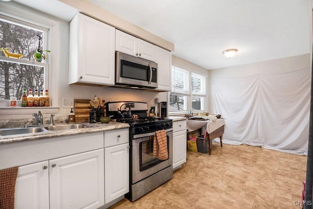 kitchen with appliances with stainless steel finishes, light countertops, white cabinets, and a sink