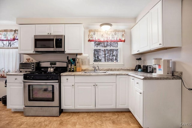 kitchen featuring appliances with stainless steel finishes, white cabinets, and a sink