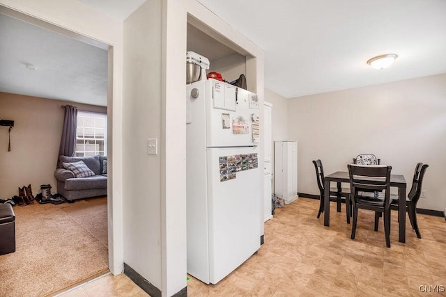 kitchen featuring freestanding refrigerator, open floor plan, white cabinetry, and baseboards