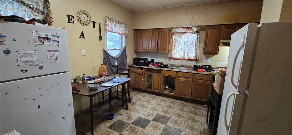 kitchen with a wealth of natural light, freestanding refrigerator, and brown cabinetry