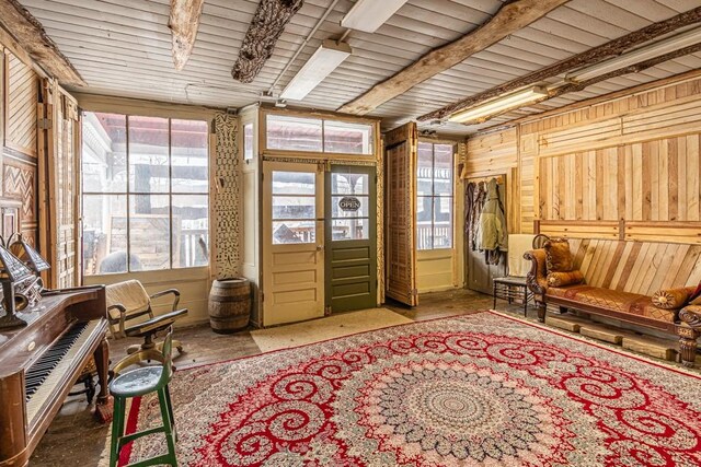 sunroom / solarium with beam ceiling, a wealth of natural light, and french doors