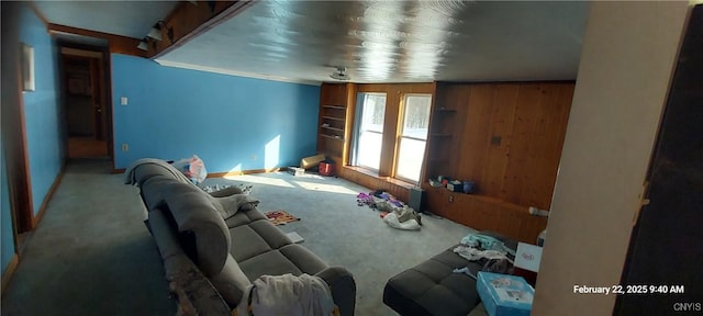 carpeted living room featuring wooden walls