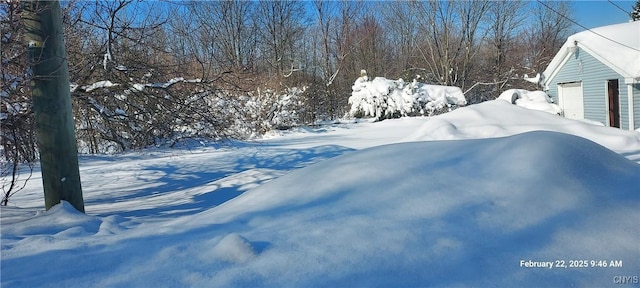 yard covered in snow featuring a detached garage