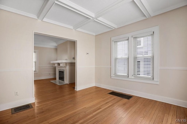 empty room featuring a fireplace with flush hearth, visible vents, coffered ceiling, and wood finished floors