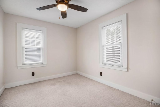 carpeted spare room featuring ceiling fan, a wealth of natural light, and baseboards