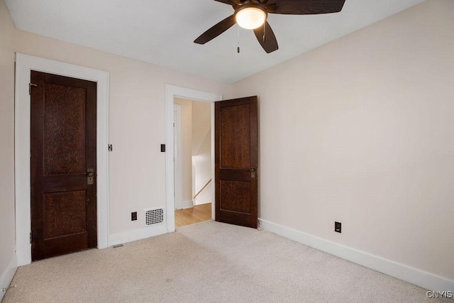 unfurnished bedroom with light carpet, a ceiling fan, visible vents, and baseboards