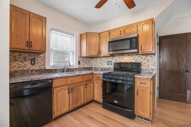 kitchen with black appliances, backsplash, light wood-type flooring, and a sink