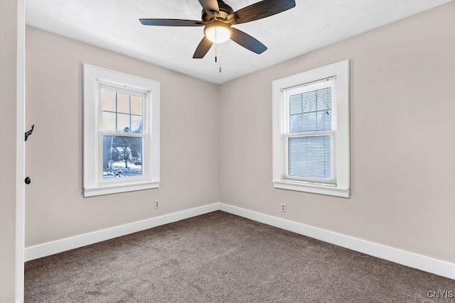 spare room with a healthy amount of sunlight, dark carpet, and baseboards