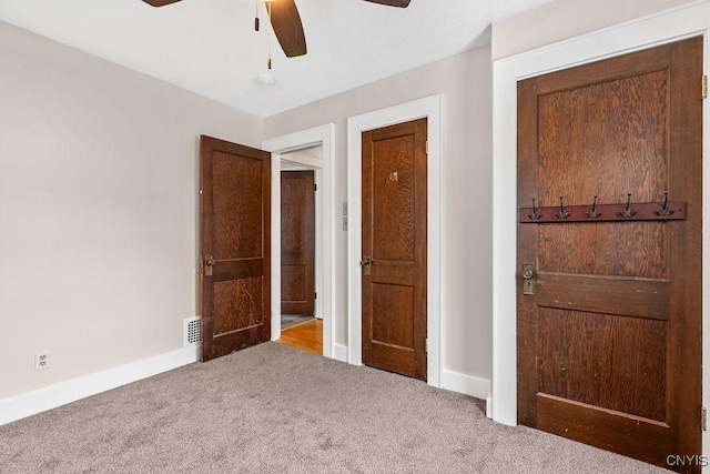 unfurnished bedroom featuring carpet floors, ceiling fan, visible vents, and baseboards