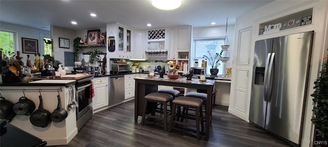 kitchen featuring a healthy amount of sunlight, white cabinetry, stainless steel appliances, and dark wood-style flooring