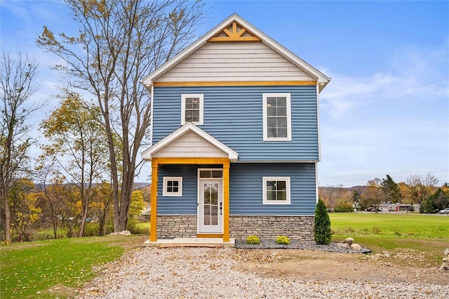 view of front of house with a front yard and stone siding