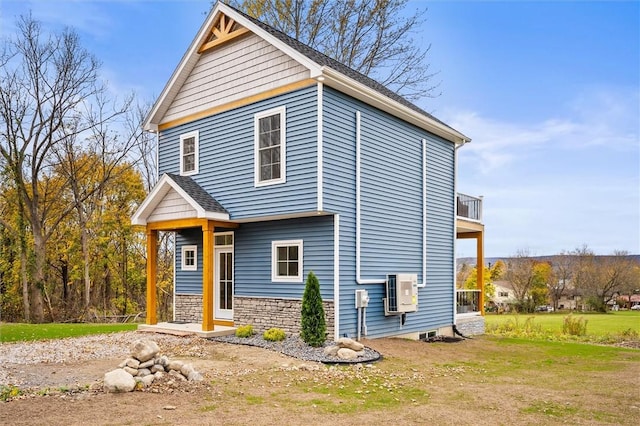 view of front facade featuring stone siding, a front lawn, and a balcony