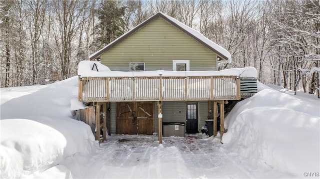 snow covered rear of property with a wooden deck