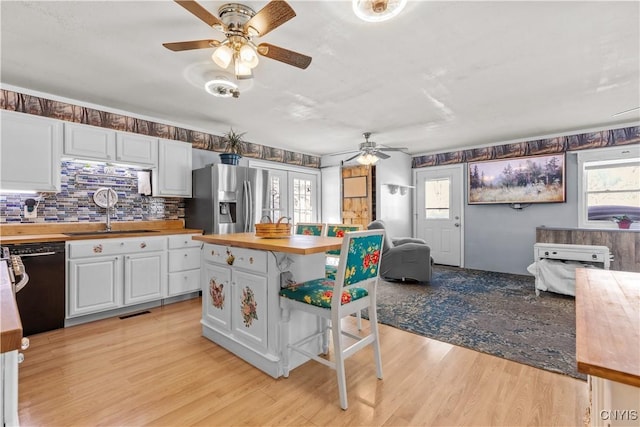 kitchen with black dishwasher, stainless steel refrigerator with ice dispenser, butcher block counters, light wood-style flooring, and a sink