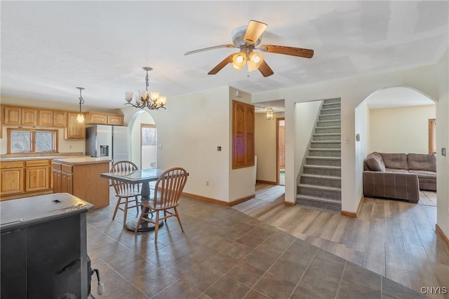 dining room featuring arched walkways, stairway, wood finished floors, and baseboards