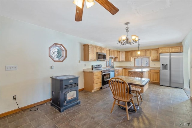 kitchen with light countertops, light brown cabinetry, appliances with stainless steel finishes, a wood stove, and a sink