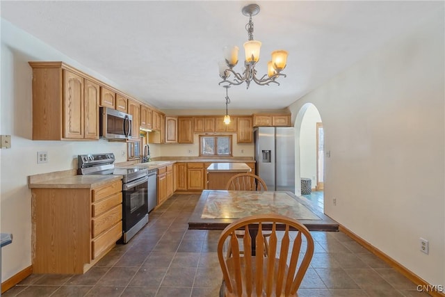 kitchen featuring appliances with stainless steel finishes, arched walkways, light countertops, and dark tile patterned flooring