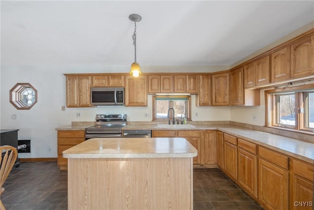 kitchen featuring a sink, light countertops, appliances with stainless steel finishes, a center island, and pendant lighting