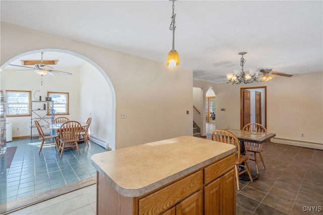 kitchen with arched walkways, ceiling fan with notable chandelier, light countertops, a center island, and pendant lighting