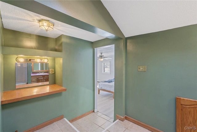 bathroom with vaulted ceiling, tile patterned flooring, a ceiling fan, and baseboards