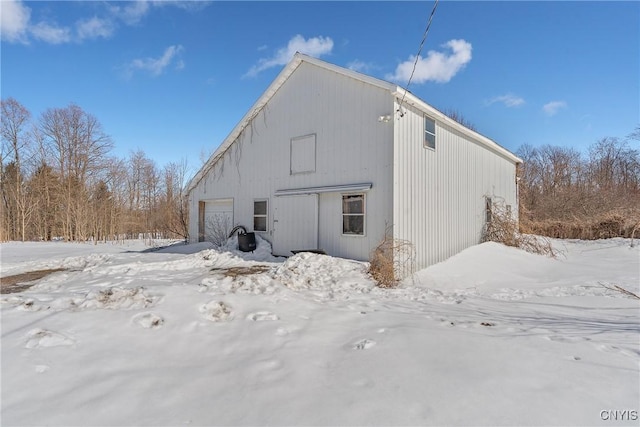 view of snow covered exterior with an outdoor structure and a detached garage