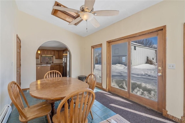 dining space featuring a baseboard heating unit, arched walkways, tile patterned floors, and a ceiling fan