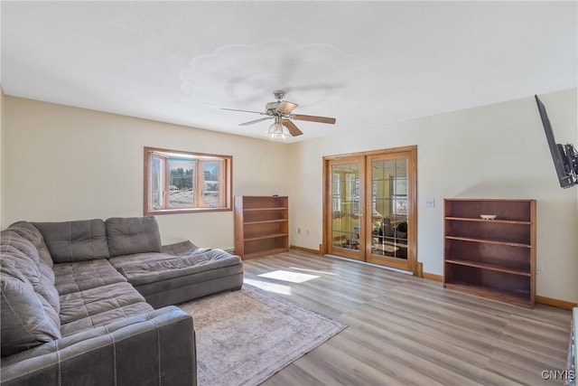 living room featuring wood finished floors, a ceiling fan, and baseboards