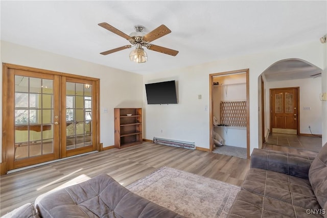 unfurnished living room featuring baseboards, arched walkways, baseboard heating, and french doors