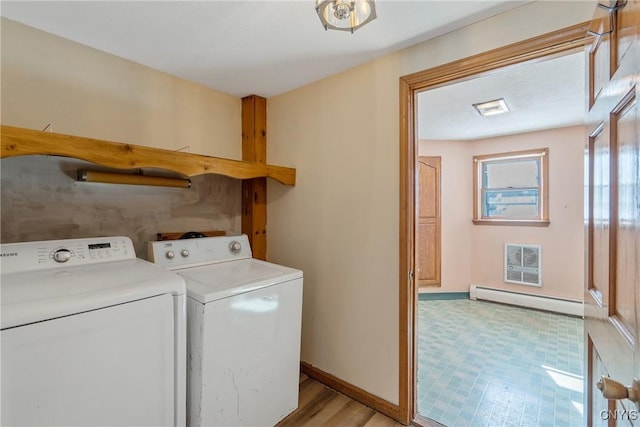 washroom with a baseboard heating unit, washing machine and dryer, laundry area, and baseboards