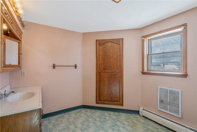 bathroom with a baseboard radiator, baseboards, an AC wall unit, and vanity