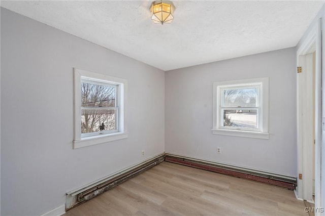 interior space with light wood-style floors, a textured ceiling, and baseboard heating