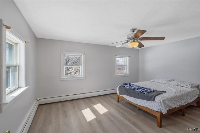 bedroom with a ceiling fan, a baseboard radiator, and wood finished floors