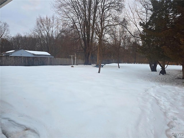 yard covered in snow featuring fence