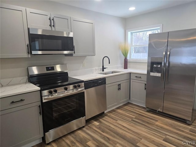 kitchen featuring dark wood-style floors, appliances with stainless steel finishes, a sink, and gray cabinetry