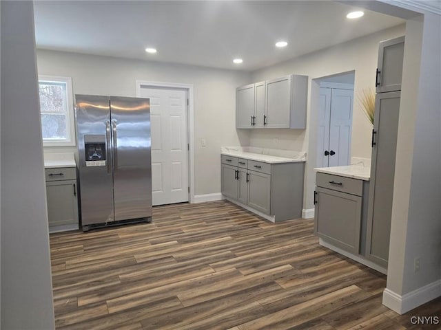 kitchen with dark wood-type flooring, light countertops, gray cabinetry, stainless steel refrigerator with ice dispenser, and recessed lighting