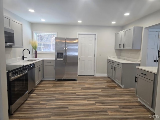 kitchen featuring stainless steel appliances, a sink, and gray cabinetry