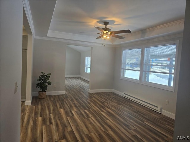 empty room with a baseboard heating unit, dark wood finished floors, baseboards, a raised ceiling, and crown molding