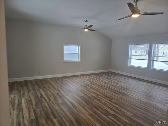 spare room featuring vaulted ceiling, dark wood-style flooring, and baseboards