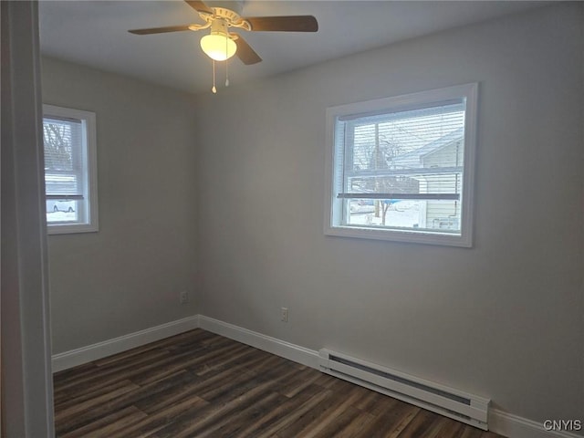 spare room with a baseboard heating unit, dark wood-style flooring, a ceiling fan, and baseboards