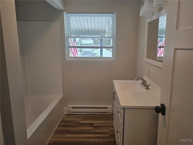 full bath featuring a wealth of natural light, baseboard heating, wood finished floors, and vanity