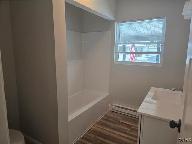 bathroom featuring toilet, wood finished floors, baseboard heating, vanity, and shower / washtub combination