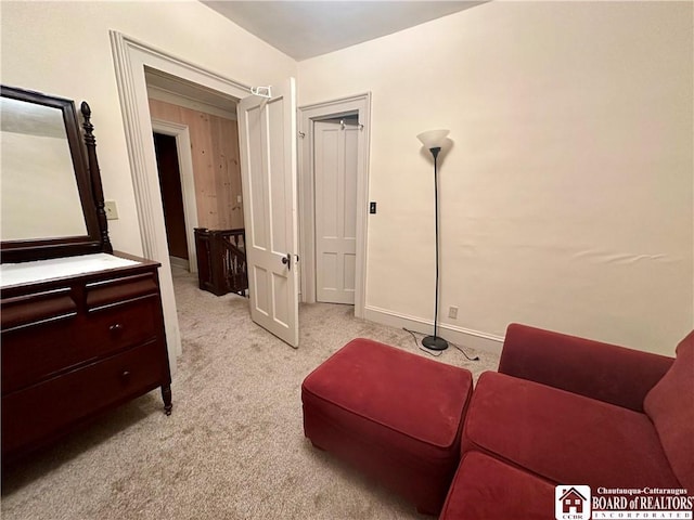 living area with baseboards and light colored carpet