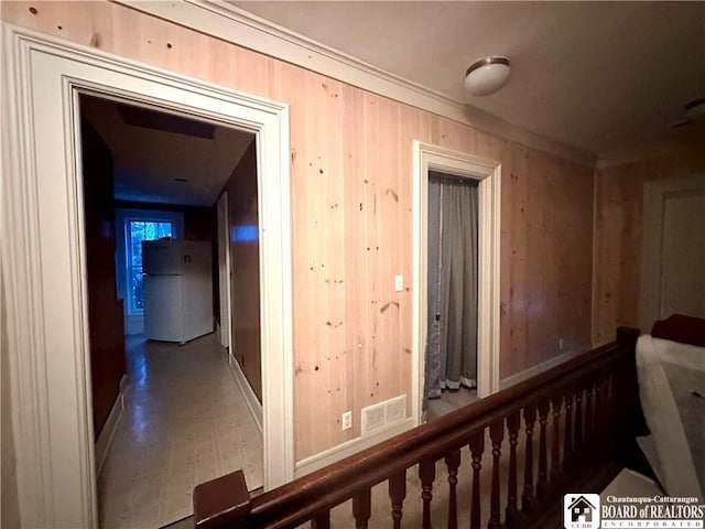 hall featuring wooden walls, visible vents, and crown molding