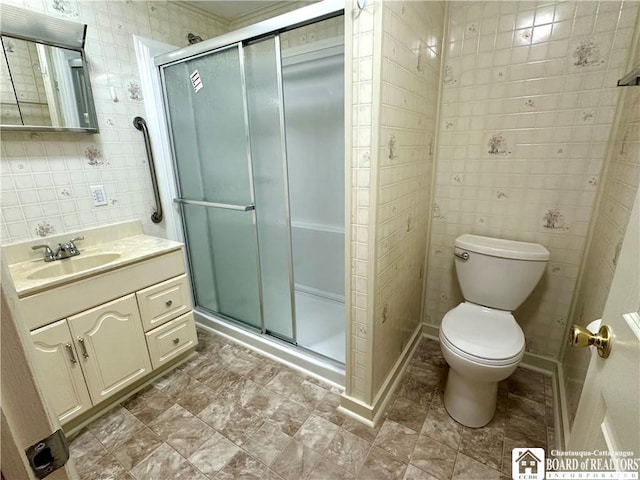 bathroom with a stall shower, vanity, toilet, and tile walls