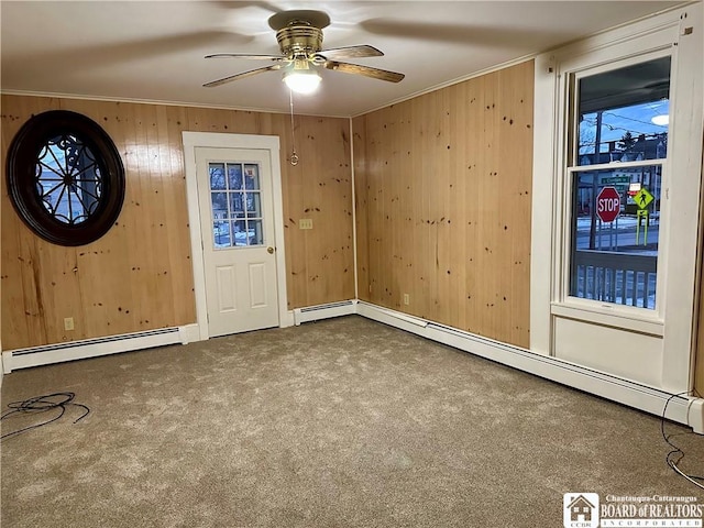 carpeted entryway with a baseboard heating unit, ornamental molding, and wooden walls