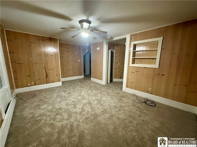 unfurnished bedroom featuring carpet floors, baseboards, wood walls, and baseboard heating