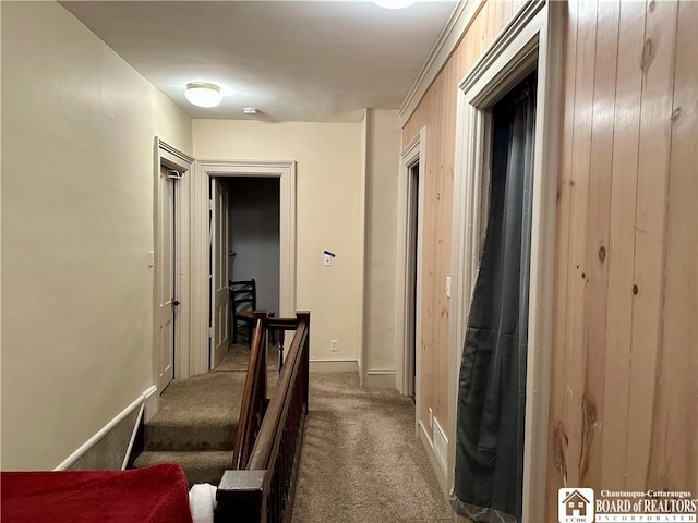 hallway with dark carpet, an upstairs landing, and baseboards